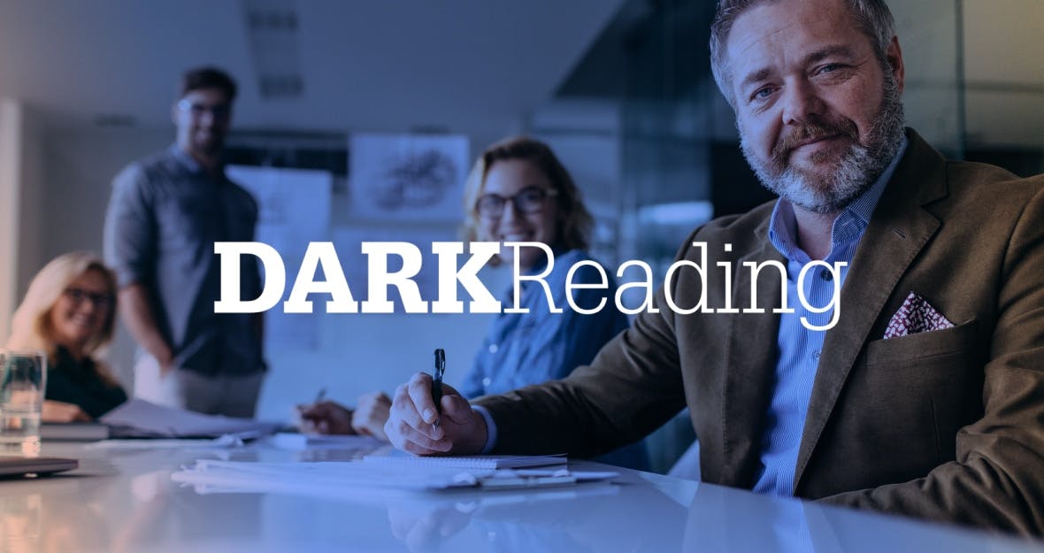 A man sits at the head of a conference table, taking notes, with three colleagues out of focus in the background. The DarkReading logo is superimposed on the image.